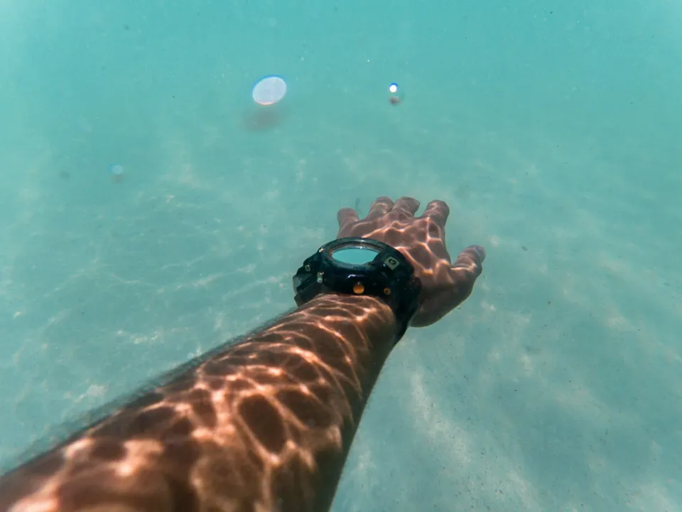 Plongeur tendant le bras sous l'eau, montre-ordinateur au poignet