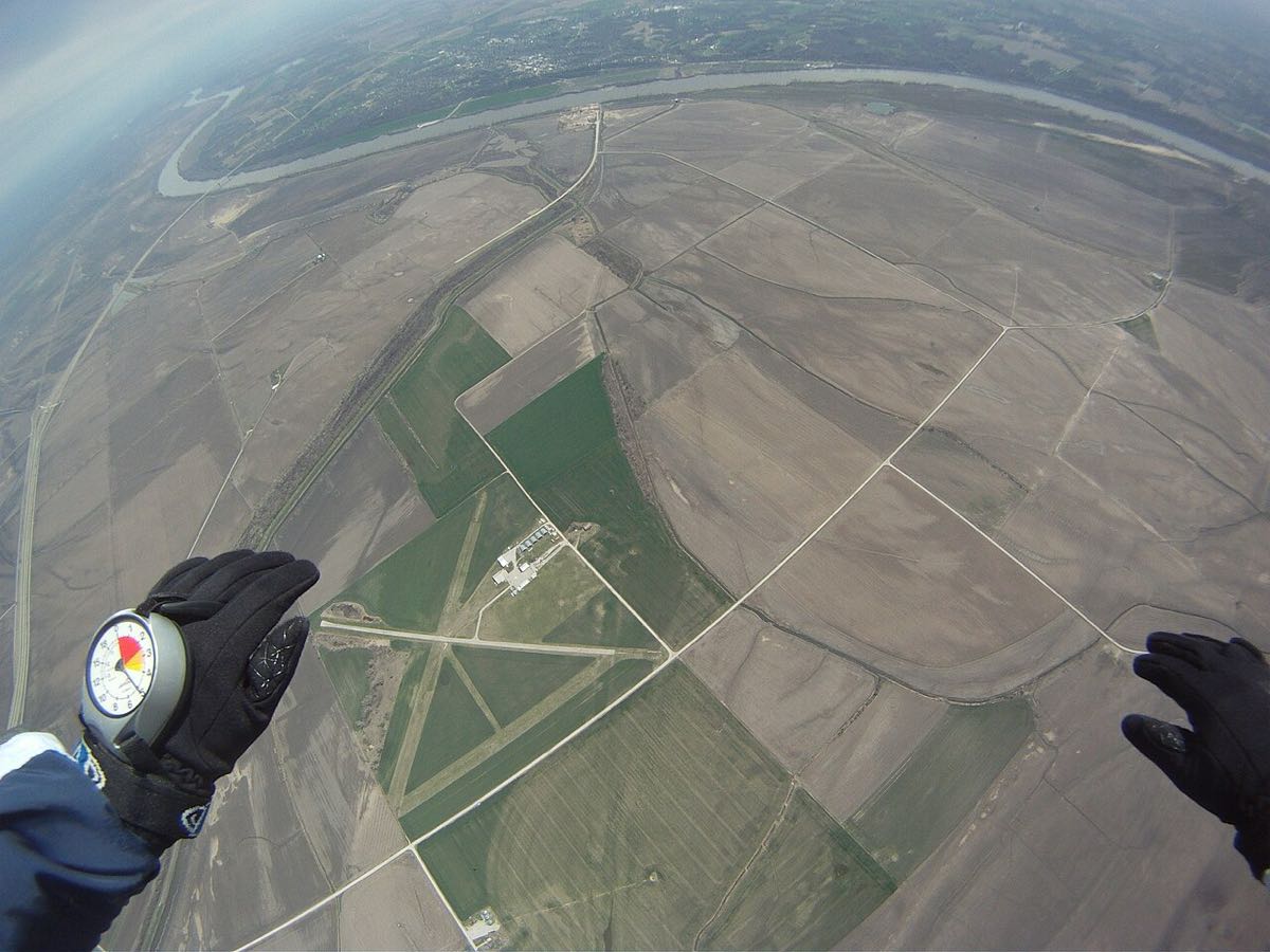 Vue en chute libre, altimètre au poignet, au-dessus des champs